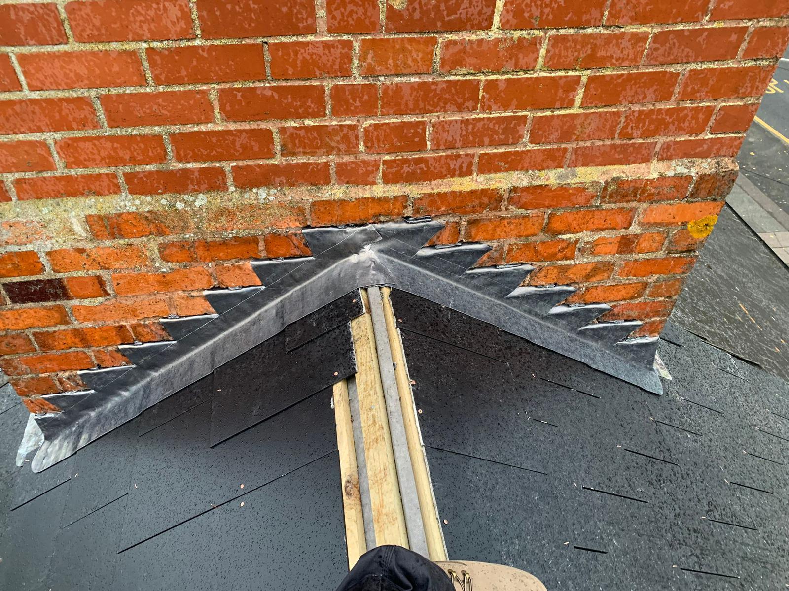 New lead flashing dressed into brickwork where a pitched roof meets a chimney stack