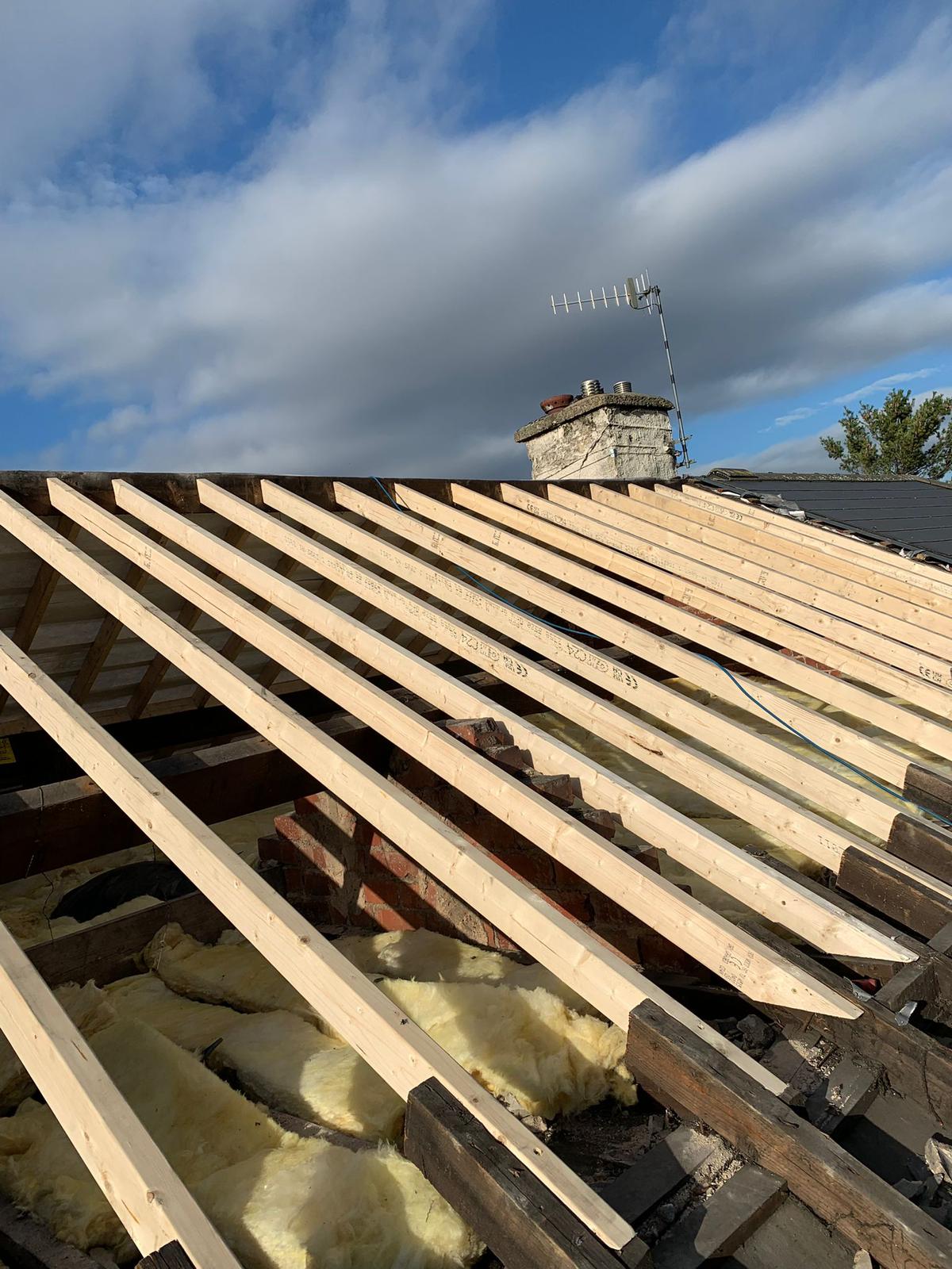 Exposed roof rafters and insulation during a complete roof strip and rebuild