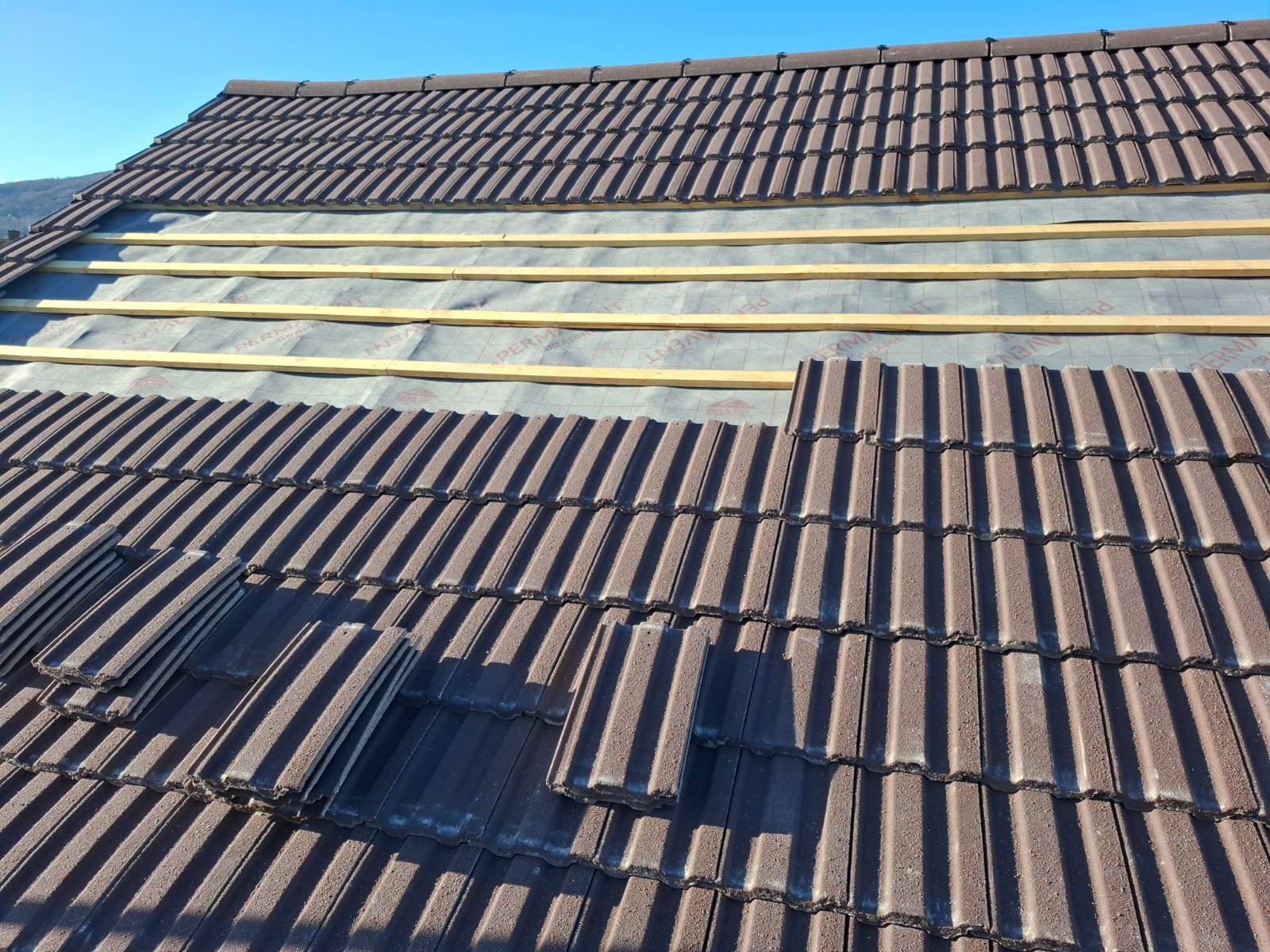 Brown concrete tile re-roof in progress with new battens and membrane